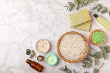 Tahta arka planda okaliptüs yapraklı güzel bir spa kompozisyonu. Vücut kremi, fırça, maske, temel yağ ve deniz tuzu içeren güzellik ve moda spa konsepti. Kozmetik ürün. Boşluğu kopyala.