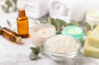 Tahta arka planda okaliptüs yapraklı güzel bir spa kompozisyonu. Vücut kremi, fırça, maske, temel yağ ve deniz tuzu içeren güzellik ve moda spa konsepti. Kozmetik ürün. Boşluğu kopyala.