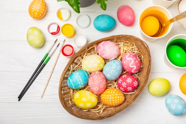 Easter egg painting at the kitchen table.Happy Easter celebration concept.Colorful Easter eggs with different patterns.Paints,decorations for coloring eggs for holiday.Creative background.Copy space