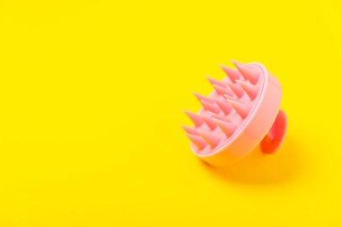 Sarı arka planda kafa masajı için fırça. Saç büyütmek için fırça, canlandırıcı fırça. Saç masajı. Uyarıcı fırça. Saç bakımı, kafa rahatlatma konsepti. Boşluğu kopyala.