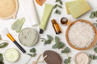 Tahta arka planda okaliptüs yapraklı güzel bir spa kompozisyonu. Vücut kremi, fırça, maske, temel yağ ve deniz tuzu içeren güzellik ve moda spa konsepti. Kozmetik ürün. Boşluğu kopyala.