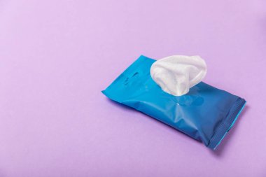 Mor arka planda ıslak mendil paketi. Açık bir el ve vücut mendili paketi. Modelleme. Temiz bir paket ıslak mendil. Tasarım. Mesaj için yer. Boşluğu kopyala.