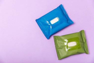 Mor arka planda ıslak mendil paketi. Açık bir el ve vücut mendili paketi. Modelleme. Temiz bir paket ıslak mendil. Tasarım. Mesaj için yer. Boşluğu kopyala.