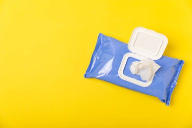 Sarı arka planda ıslak mendil paketi. Açık bir el ve vücut mendili paketi. Modelleme. Temiz bir paket ıslak mendil. Tasarım. Mesaj için yer. Boşluğu kopyala.