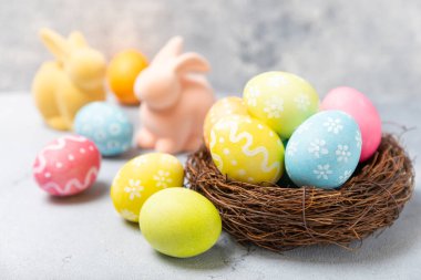 Yuvasında parlak bir arka planda mimoza çiçekleri olan Paskalya yumurtaları. Paskalya kutlaması. El yapımı renkli Paskalya yumurtaları. Mesaj için yer. Boşluğu kopyala.