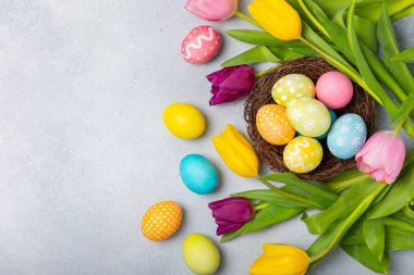 Yuvasında parlak bir arka planda mimoza çiçekleri olan Paskalya yumurtaları. Paskalya kutlaması. El yapımı renkli Paskalya yumurtaları. Mesaj için yer. Boşluğu kopyala.