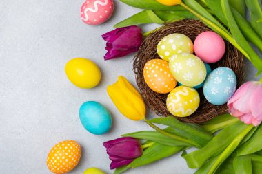 Yuvasında parlak bir arka planda mimoza çiçekleri olan Paskalya yumurtaları. Paskalya kutlaması. El yapımı renkli Paskalya yumurtaları. Mesaj için yer. Boşluğu kopyala.