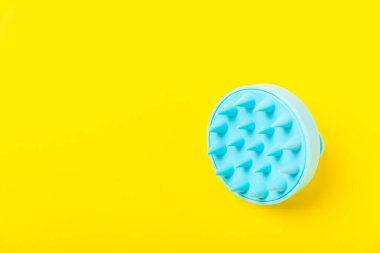 Sarı arka planda kafa masajı için fırça. Saç büyütmek için fırça, canlandırıcı fırça. Saç masajı. Uyarıcı fırça. Saç bakımı, kafa rahatlatma konsepti. Boşluğu kopyala.