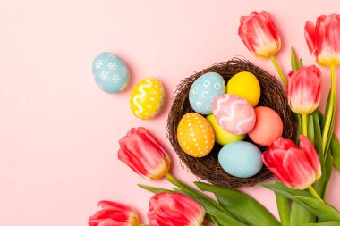 Paskalya yumurtaları ve parlak bir arka planda bir buket lale. Paskalya kutlaması. El yapımı renkli Paskalya yumurtaları. Mesaj için yer. Boşluğu kopyala.