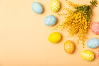 Parlak bir arka planda mimoza çiçekli Paskalya yumurtaları. Paskalya kutlaması. El yapımı renkli Paskalya yumurtaları. Mesaj için yer. Boşluğu kopyala.