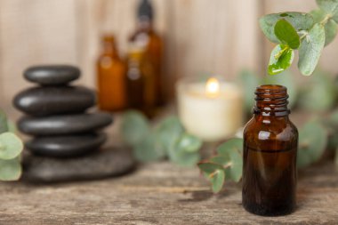 Okaliptüs, ahşap kaplamalı yeşil okaliptüs yapraklı cam bir şişede gerekli yağdır. Aromaterapi konsepti. Spa mı? Kozmetik ve vücut bakımı için doğal organik malzemeler.