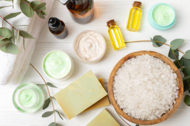 Tahta arka planda okaliptüs yapraklı güzel bir spa kompozisyonu. Vücut kremi, fırça, maske, temel yağ ve deniz tuzu içeren güzellik ve moda spa konsepti. Kozmetik ürün. Boşluğu kopyala.