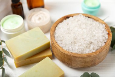 Tahta arka planda okaliptüs yapraklı güzel bir spa kompozisyonu. Vücut kremi, fırça, maske, temel yağ ve deniz tuzu içeren güzellik ve moda spa konsepti. Kozmetik ürün. Boşluğu kopyala.