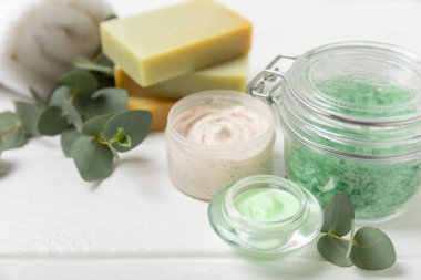 Tahta arka planda okaliptüs yapraklı güzel bir spa kompozisyonu. Vücut kremi, fırça, maske, temel yağ ve deniz tuzu içeren güzellik ve moda spa konsepti. Kozmetik ürün. Boşluğu kopyala.