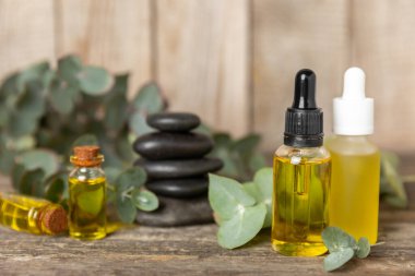 Okaliptüs, ahşap kaplamalı yeşil okaliptüs yapraklı cam bir şişede gerekli yağdır. Aromaterapi konsepti. Spa mı? Kozmetik ve vücut bakımı için doğal organik malzemeler.