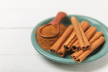 Tarçınlı çubuklar ahşap bir arka planda. Tarçınlı rulo. Fırın, tatlı ve içecekler için baharatlı baharat. Güzel kokulu tarçın. Tarçın tozu yakın plan. Mesaj için yer. Boşluğu kopyala