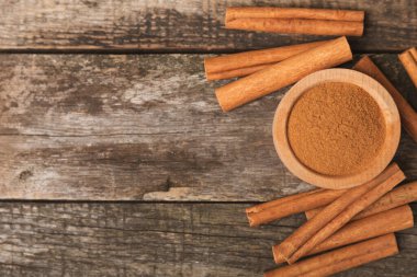 Tarçınlı çubuklar ahşap bir arka planda. Tarçınlı rulo. Fırın, tatlı ve içecekler için baharatlı baharat. Güzel kokulu tarçın. Tarçın tozu yakın plan. Mesaj için yer. Boşluğu kopyala