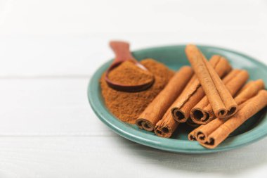 Tarçınlı çubuklar ahşap bir arka planda. Tarçınlı rulo. Fırın, tatlı ve içecekler için baharatlı baharat. Güzel kokulu tarçın. Tarçın tozu yakın plan. Mesaj için yer. Boşluğu kopyala