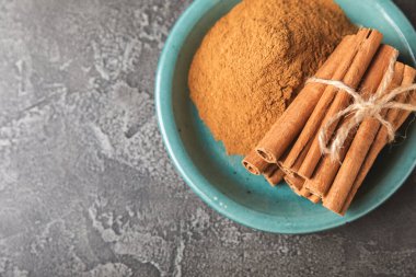 Tarçınlı çubuklar ahşap bir arka planda. Tarçınlı rulo. Fırın, tatlı ve içecekler için baharatlı baharat. Güzel kokulu tarçın. Tarçın tozu yakın plan. Mesaj için yer. Boşluğu kopyala