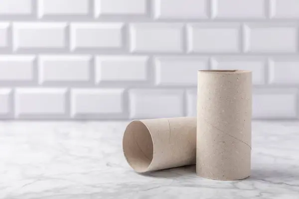 Empty toilet paper roll. Empty toilet paper rolls on marble background. Paper tube of toilet paper. Place for text. Copy space. Flat lay. Eco-friendly reuse recycle