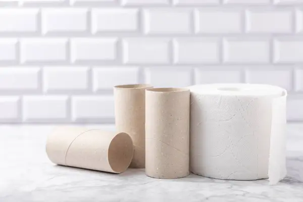 Empty toilet paper roll. Empty toilet paper rolls on marble background. Paper tube of toilet paper. Place for text. Copy space. Flat lay. Eco-friendly reuse recycle