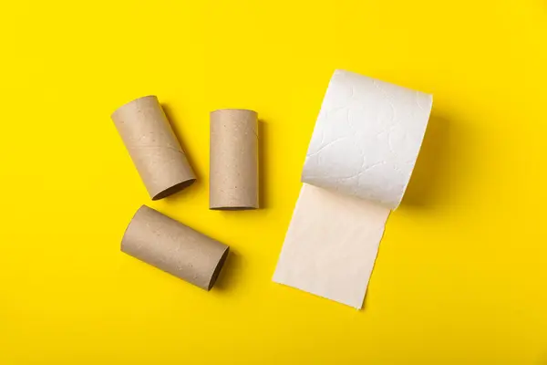 Empty toilet paper roll. Empty rolls and a new roll of toilet paper for the toilet, on a bright yellow background. Paper tube of toilet paper. Place for text. Copy space. Flat lay. Eco-friendly reuse recycle