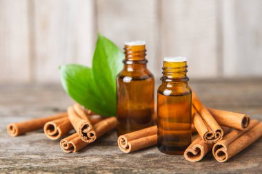 Tarçın aromatik gerekli yağ ve tarçın çubukları ahşap bir arka planda. Aromaterapi. Organik kozmetik yağı. Spa konsepti. Mesaj için yer. Boşluğu kopyala.