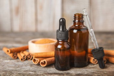 Tarçın aromatik gerekli yağ ve tarçın çubukları ahşap bir arka planda. Aromaterapi. Organik kozmetik yağı. Spa konsepti. Mesaj için yer. Boşluğu kopyala.