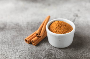 Ahşap kaplamalı bir kasede tarçın tozu. Fırın, tatlı ve içecekler için baharatlı baharat. Güzel kokulu tarçın. Tarçın çubuğu. Mesaj için yer. Boşluğu kopyala.