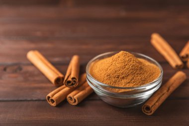 Ahşap kaplamalı bir kasede tarçın tozu. Fırın, tatlı ve içecekler için baharatlı baharat. Güzel kokulu tarçın. Tarçın çubuğu. Mesaj için yer. Boşluğu kopyala.