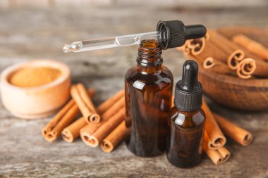 Tarçın aromatik gerekli yağ ve tarçın çubukları ahşap bir arka planda. Aromaterapi. Organik kozmetik yağı. Spa konsepti. Mesaj için yer. Boşluğu kopyala.