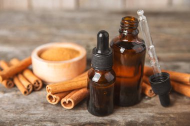 Tarçın aromatik gerekli yağ ve tarçın çubukları ahşap bir arka planda. Aromaterapi. Organik kozmetik yağı. Spa konsepti. Mesaj için yer. Boşluğu kopyala.