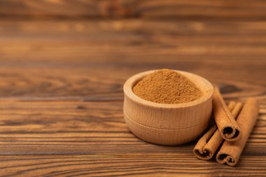 Tarçınlı çubuklar ahşap bir arka planda. Tarçınlı rulo. Fırın, tatlı ve içecekler için baharatlı baharat. Güzel kokulu tarçın. Tarçın tozu yakın plan. Mesaj için yer. Boşluğu kopyala