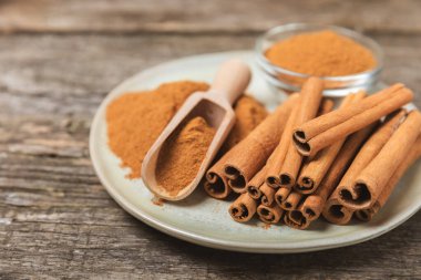 Tarçınlı çubuklar ahşap bir arka planda. Tarçınlı rulo. Fırın, tatlı ve içecekler için baharatlı baharat. Güzel kokulu tarçın. Tarçın tozu yakın plan. Mesaj için yer. Boşluğu kopyala