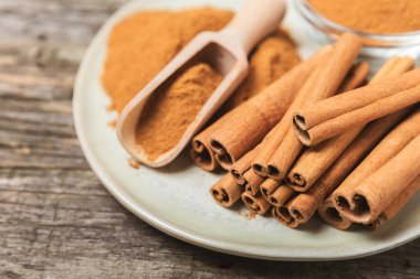 Tarçınlı çubuklar ahşap bir arka planda. Tarçınlı rulo. Fırın, tatlı ve içecekler için baharatlı baharat. Güzel kokulu tarçın. Tarçın tozu yakın plan. Mesaj için yer. Boşluğu kopyala