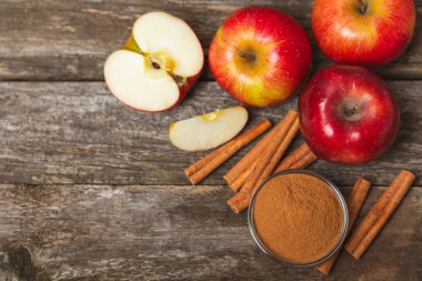 Tarçınlı elmalar ahşap kaplamalı. Tarçın çubukları ve yıldız anason ile kokulu kırmızı elmalar. Baharatlı elma dilimleri. Mesaj için yer. Uzayı kopyala Hasat. Meyveler. Vejetaryen.