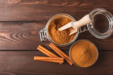 Ahşap kaplamalı bir kasede tarçın tozu. Fırın, tatlı ve içecekler için baharatlı baharat. Güzel kokulu tarçın. Tarçın çubuğu. Mesaj için yer. Boşluğu kopyala.