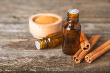 Tarçın aromatik gerekli yağ ve tarçın çubukları ahşap bir arka planda. Aromaterapi. Organik kozmetik yağı. Spa konsepti. Mesaj için yer. Boşluğu kopyala.