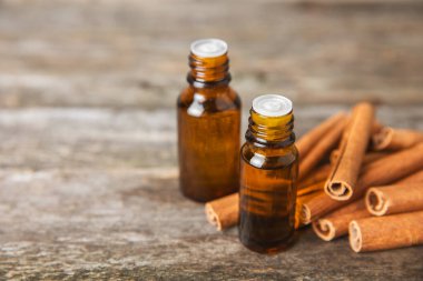 Tarçın aromatik gerekli yağ ve tarçın çubukları ahşap bir arka planda. Aromaterapi. Organik kozmetik yağı. Spa konsepti. Mesaj için yer. Boşluğu kopyala.