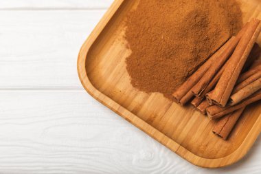 Tarçınlı çubuklar ahşap bir arka planda. Tarçınlı rulo. Fırın, tatlı ve içecekler için baharatlı baharat. Güzel kokulu tarçın. Tarçın tozu yakın plan. Mesaj için yer. Boşluğu kopyala