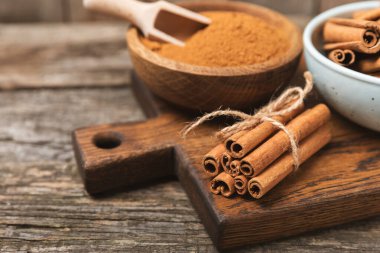 Tarçınlı çubuklar ahşap bir arka planda. Tarçınlı rulo. Fırın, tatlı ve içecekler için baharatlı baharat. Güzel kokulu tarçın. Tarçın tozu yakın plan. Mesaj için yer. Boşluğu kopyala