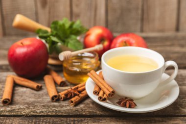 Tarçın sopasıyla kokulu sıcak çay ve ahşap bir arka planda anason. Ballı, limonlu, naneli ve elmalı bir fincan sıcak çay. Baharatlı baharatlı çay. Dokunulmazlık çayı. Sağlık kavramı. Boşluğu kopyala.