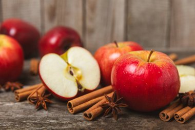 Tarçınlı elmalar ahşap kaplamalı. Tarçın çubukları ve yıldız anason ile kokulu kırmızı elmalar. Baharatlı elma dilimleri. Mesaj için yer. Uzayı kopyala Hasat. Meyveler. 