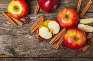 Tarçınlı elmalar ahşap kaplamalı. Tarçın çubukları ve yıldız anason ile kokulu kırmızı elmalar. Baharatlı elma dilimleri. Mesaj için yer. Uzayı kopyala Hasat. Meyveler. 