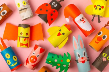 Renkli arka planda tuvalet kağıdı işçiliği. Tuvalet kağıdı rulosundan yapılmış çocuk el sanatları. DIY. El yapımı. Kağıt oyuncaklar. Origami hayvanları. Çocukların eğitici oyunları kavramı. Mesaj için yer. Boşluğu kopyala.