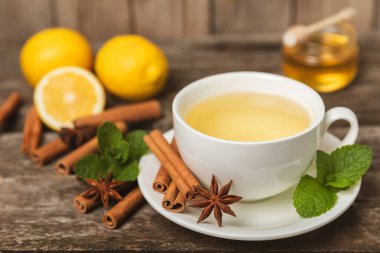 Tarçın sopasıyla kokulu sıcak çay ve ahşap bir arka planda anason. Ballı, limonlu, naneli ve elmalı bir fincan sıcak çay. Baharatlı baharatlı çay. Dokunulmazlık çayı. Sağlık kavramı. Boşluğu kopyala.