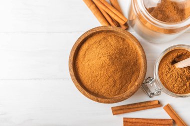 Ahşap kaplamalı bir kasede tarçın tozu. Fırın, tatlı ve içecekler için baharatlı baharat. Güzel kokulu tarçın. Tarçın çubuğu. Mesaj için yer. Boşluğu kopyala.