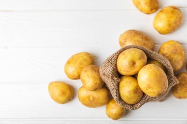 Genç patatesler Ahşap zeminde taze patates. Çuvalda patates. Hasat koleksiyonu. organik, taze kazılmış patatesler. Tarım geçmişi. Vejetaryen. Sebzeler. Mesajlar için yer. Boşluğu kopyala