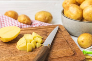 Genç patatesler Ahşap zeminde çiğ patates ve bıçak. Patates soy. Hasat topla. organik, taze kazılmış patatesler. Tarım geçmişi. Vejetaryen. Sebzeler. Mesajlar için yer. Boşluğu kopyala