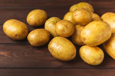 Genç patatesler Tahta zeminde taze patates. Hasat koleksiyonu. organik, taze kazılmış patatesler. Tarım geçmişi. Vejetaryen. Sebzeler. Mesajlar için yer. Boşluğu kopyala